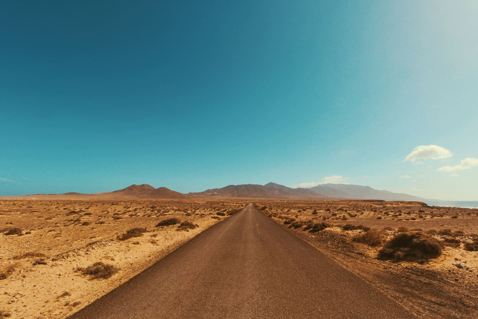 A road running straight through open desert towards distant hills.