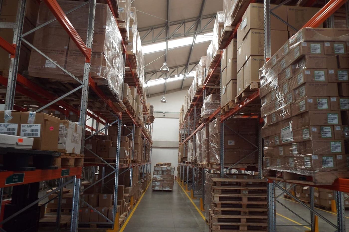 An aisle of stacked and wrapped pallets in a distribution warehouse.